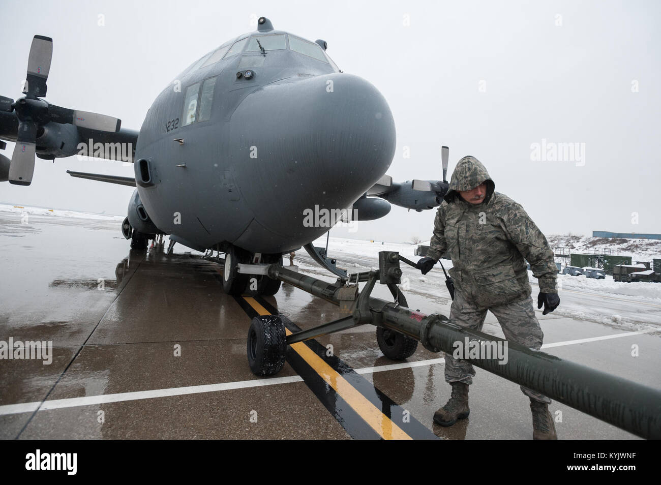 Master Sgt. Carl Shaffer, a C-130 crew chief in the 123rd Aircraft Maintenance Squadron, works to disconnect a tow bar from a C-130 Hercules aircraft on the flight line of the Kentucky Air National Guard Base in Louisville, Ky., Feb. 21, 2015. The aircraft, which subsequently departed for the Persian Gulf along with 37 deploying Kentucky Air Guardsmen, was being housed in a hangar because of severe weather conditions. (U.S. Air National Guard photo by Maj. Dale Greer) Stock Photo