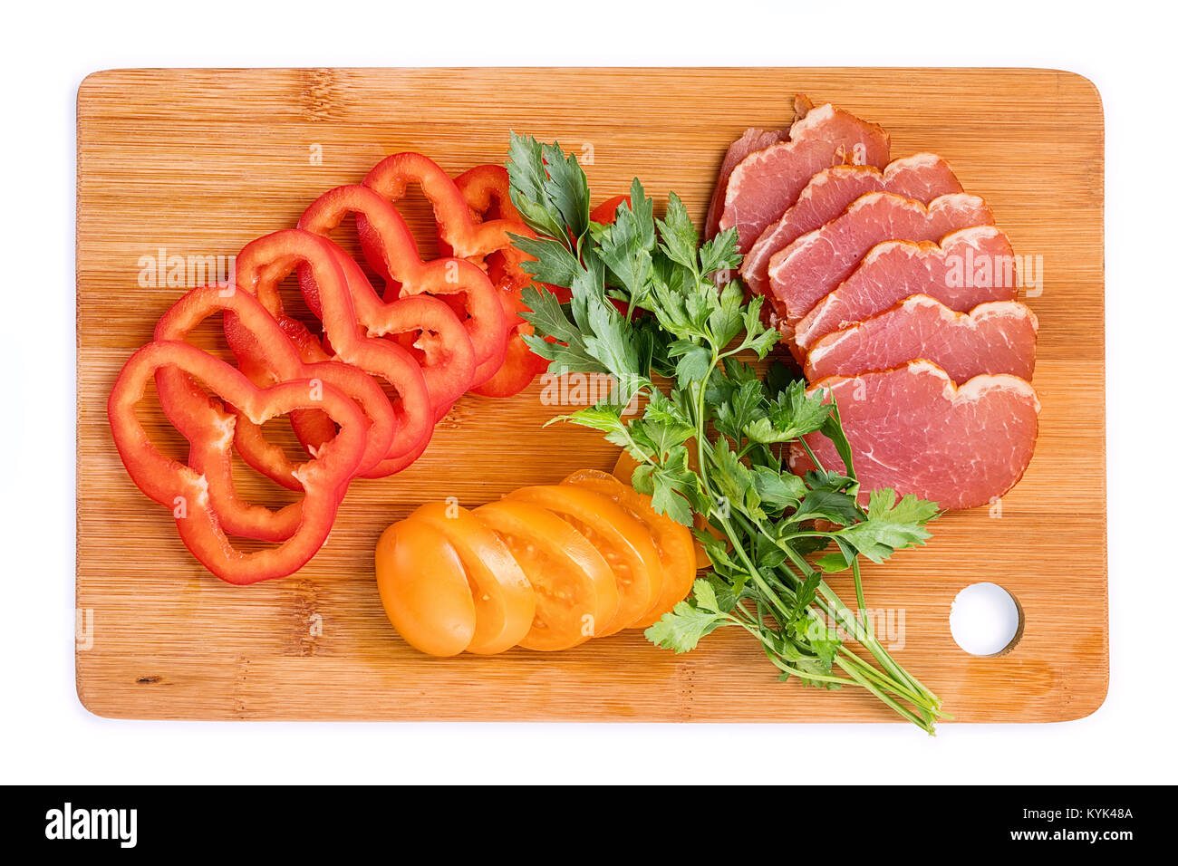 Raw food on the cutting board top view. Tomatoes, peppers, meat and greens on a wooden board. Isolated on white Stock Photo