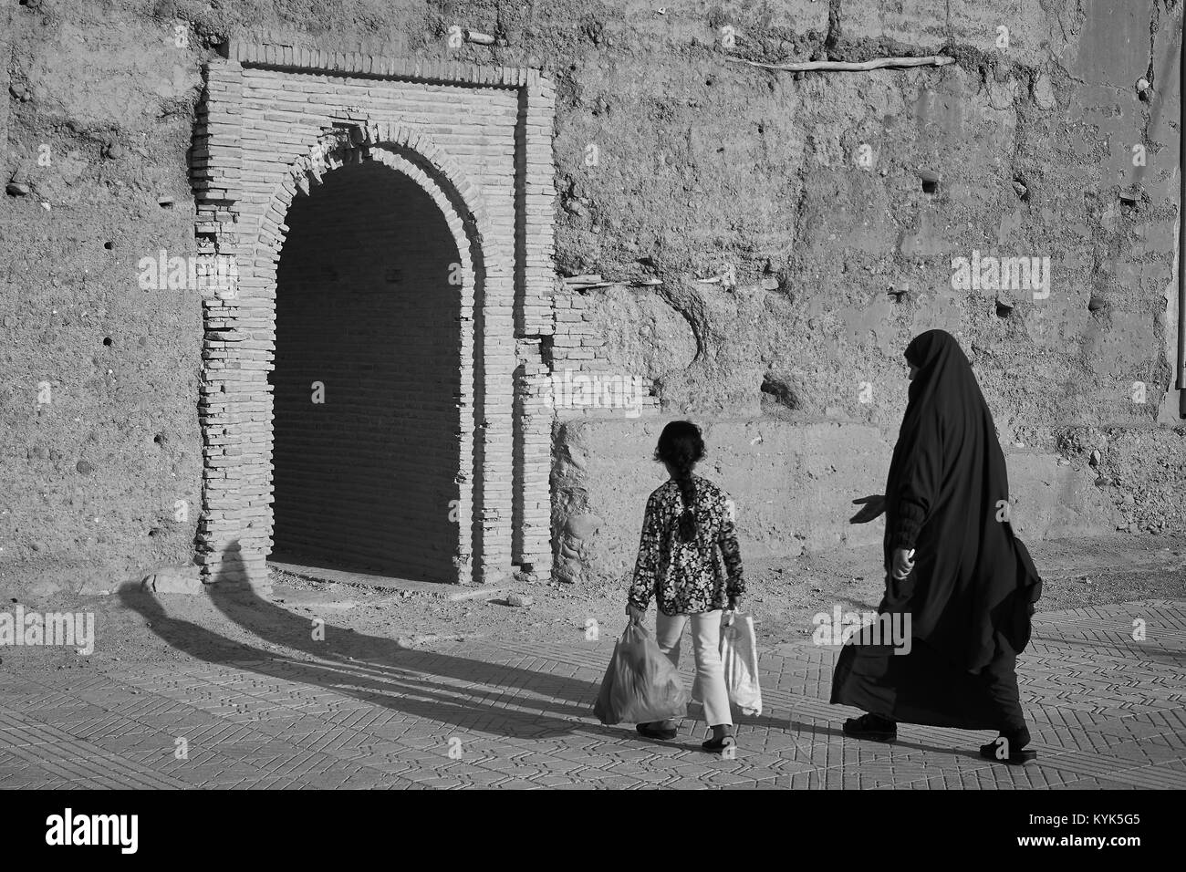 Morrocan veiled woman and little girl walking to fortification door, Taroudant, Morocco Stock Photo