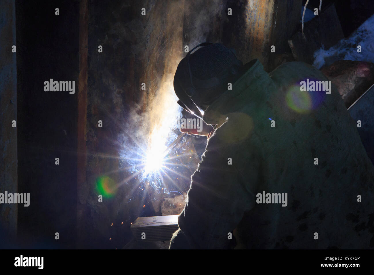 Welder from the back, in backlight from electric welding. Stock Photo
