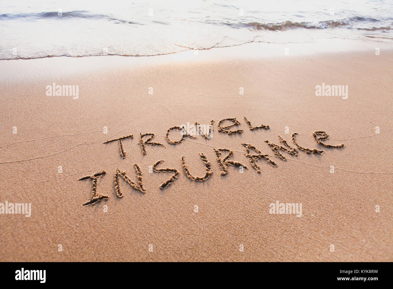 travel insurance concept, text words written on the sand Stock Photo