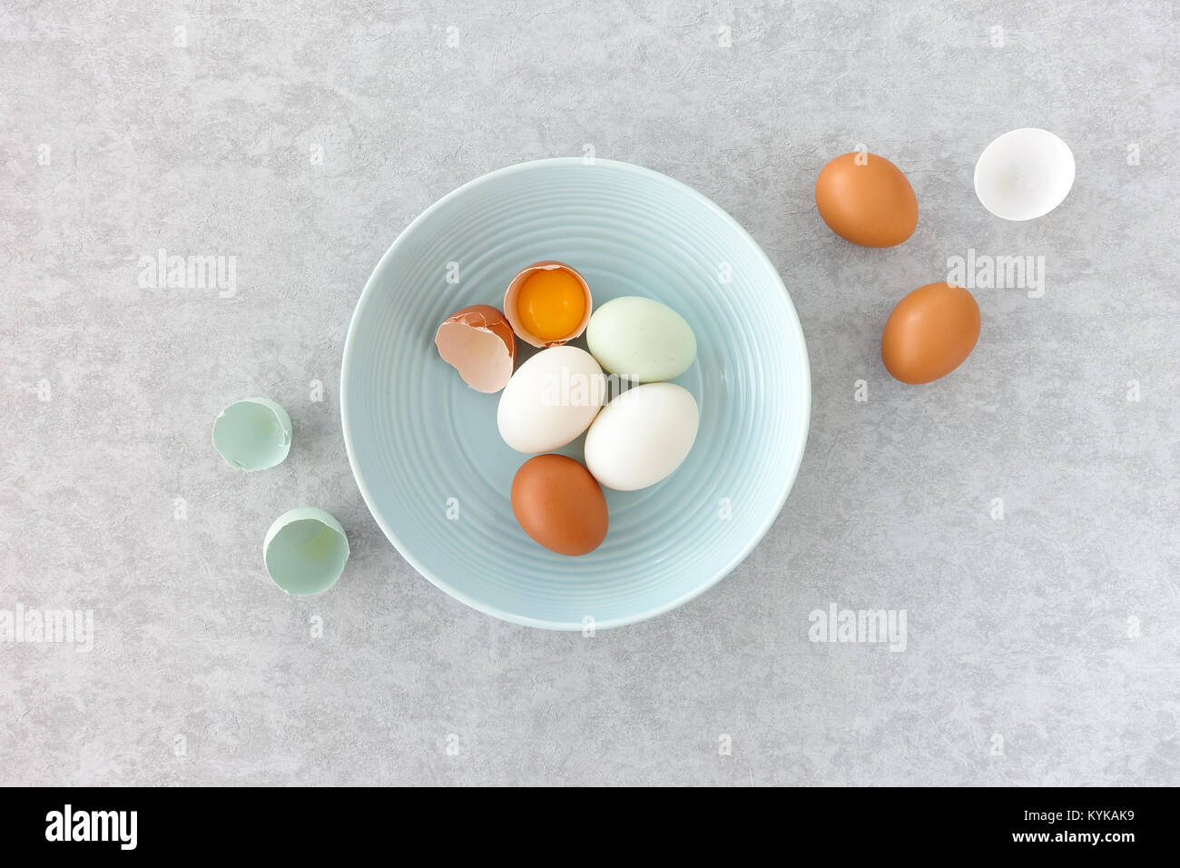 Blue eggs, brown eggs and duck eggs, whole and halves, in a pastel blue