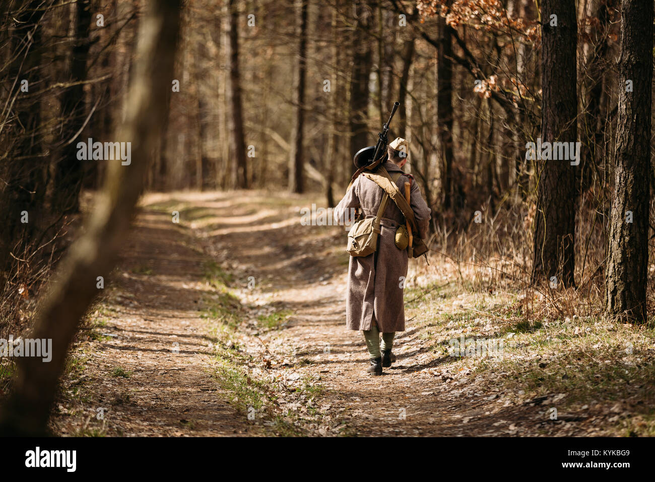 Young unidentified re-enactor dressed as Soviet soldier machine gunner goes along a forest road Stock Photo