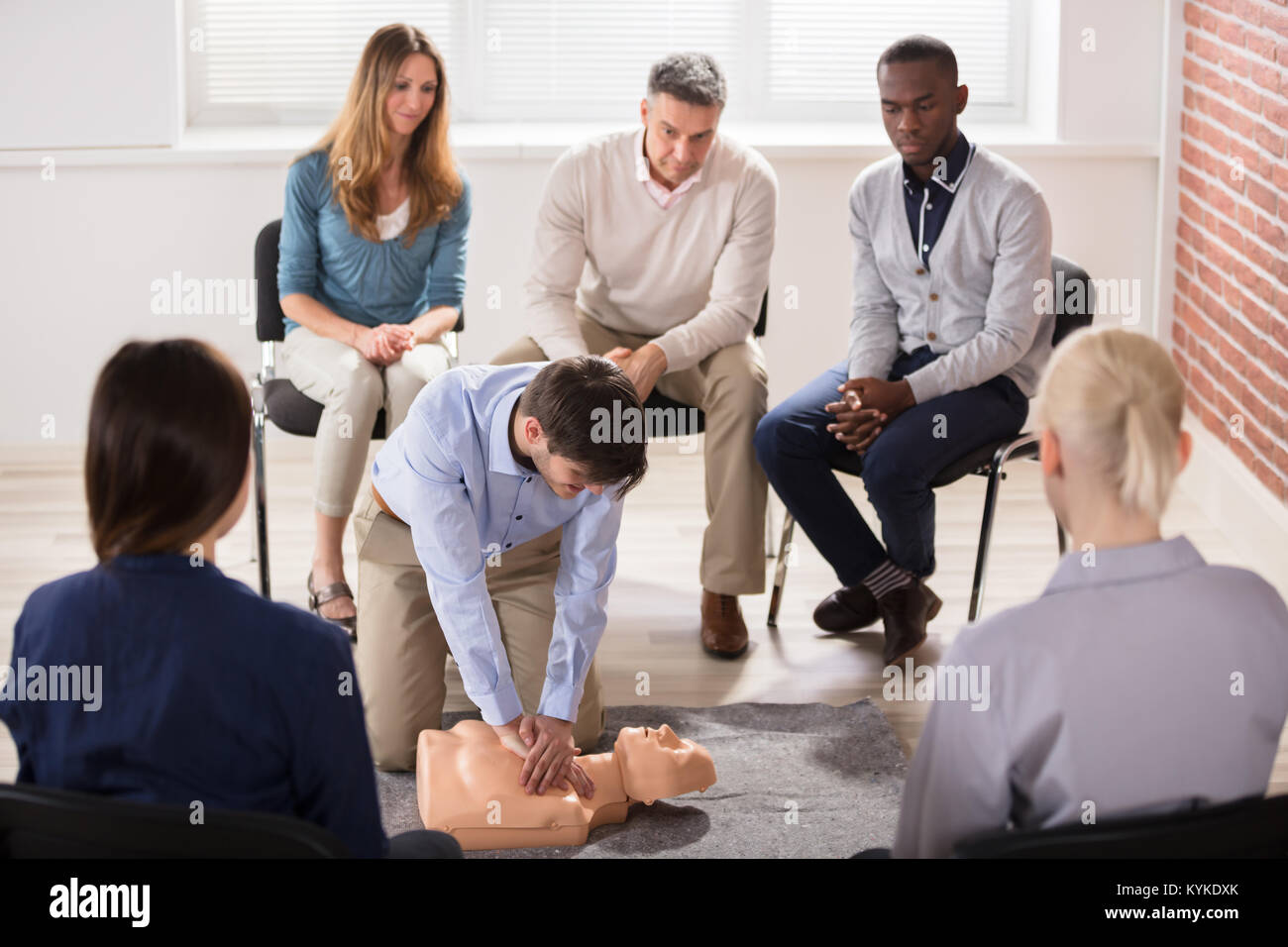Young Male Instructor Showing CPR Training On Dummy To His Student Stock Photo