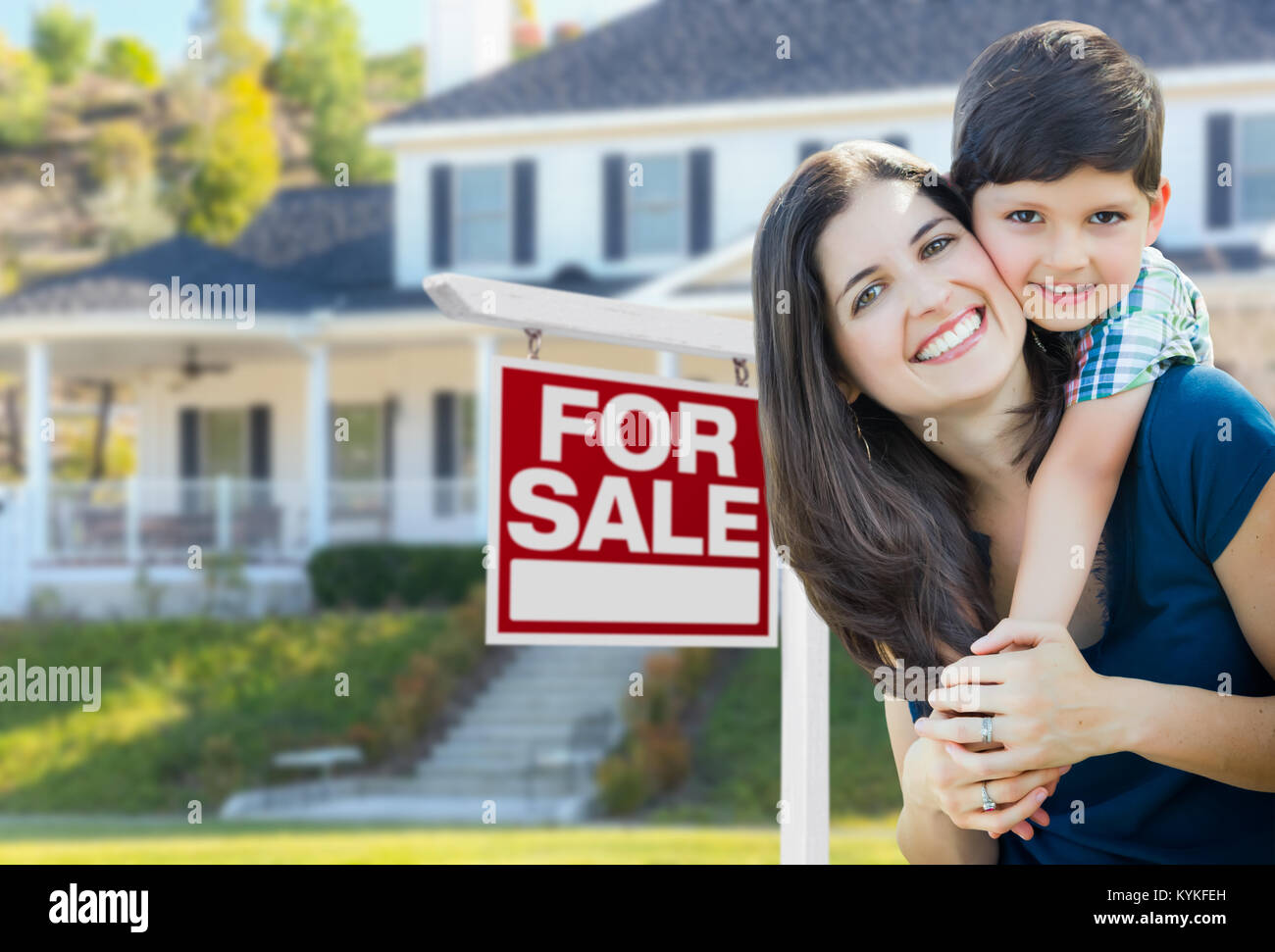 Young Mother and Son In Front of For Sale Real Estate Sign and House