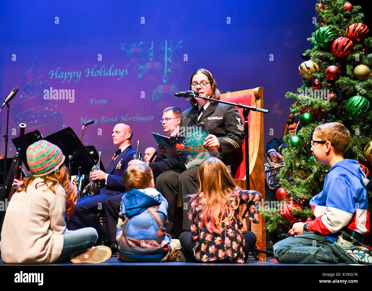 EVERETT, Wash. (Dec. 11, 2017) Musician 1st Class Jennifer Gions, reads to children during a performance featuring Navy Band Northwest and U.S. Air Force Band of the Golden West during the Season's Greetings holiday concert at the Everett Performing Arts Center. Navy Band Northwest is one of eleven official U.S. Navy Bands located around the world. (U.S. Navy photo by Mass Communication Specialist 2nd Class Joseph Montemarano/Released)171211-N-WX604-0388 Stock Photo