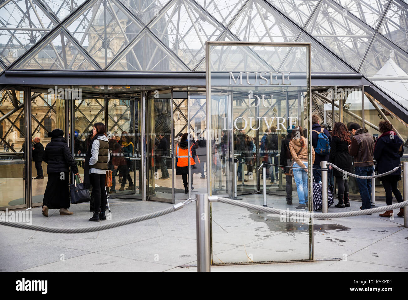 PARIS, FRANCE - JAN 5, 2014: Visitors line up at the glass entrance to the Louvre Museum. The vast museum is among the most famous in the world. Stock Photo