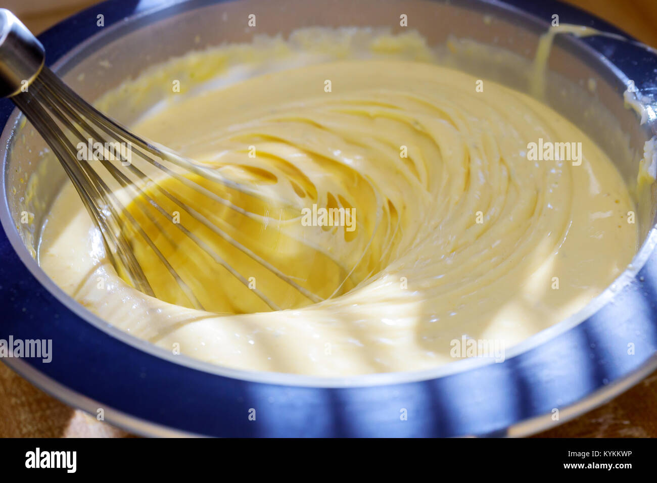 Closeup of electric mixer with whipped smooth dough for cake. Batter being whipped. Mixing white dough in bowl with motor mixer, baking cake Stock Photo