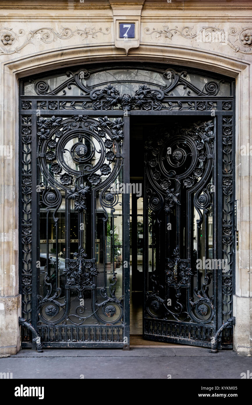 Paris art nouveau iron and glass double doors in an ornate design. One door is partly open from the street. Number 7. Stock Photo