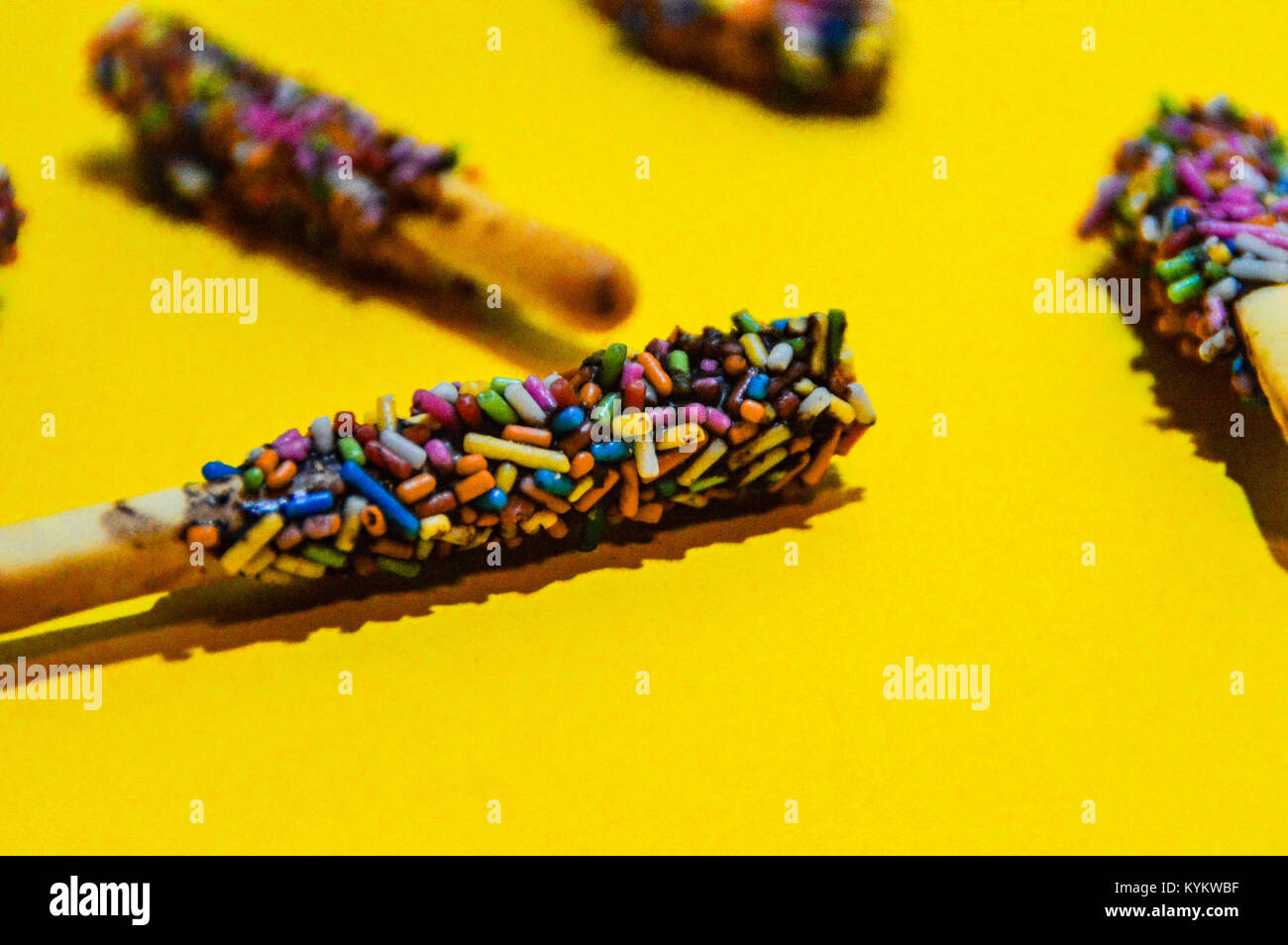Colorful candies against a bright yellow colored background Stock Photo
