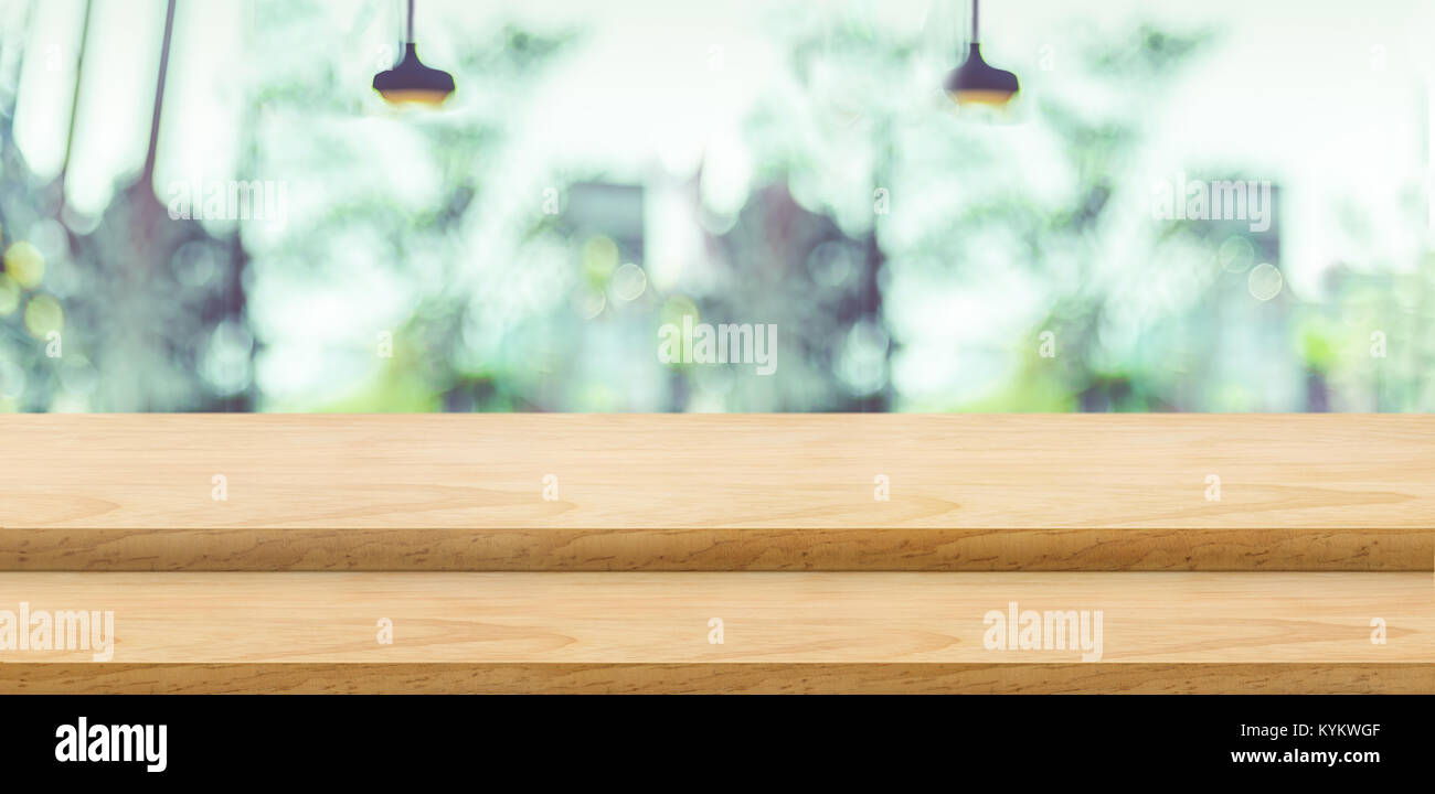 Empty step wood table top ( food stand ) with blur green tree at restaurant window with lamp background bokeh light,Mock up for display or montage of  Stock Photo
