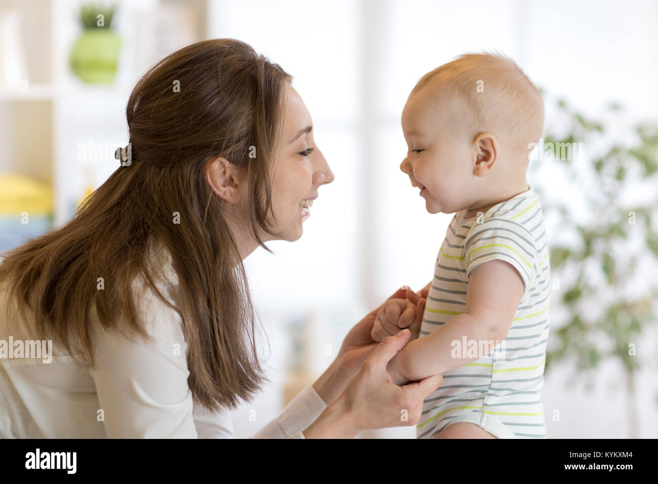 cute little baby plays with his young mom in bedroom Stock Photo