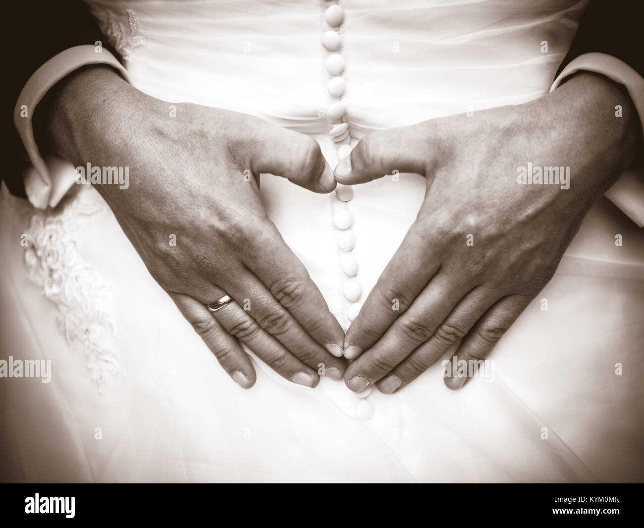 the Groom creating heart shape with his hands on the back of the bride.Couple in love. Close up of hands. Young couple has done heart shape hands in t Stock Photo