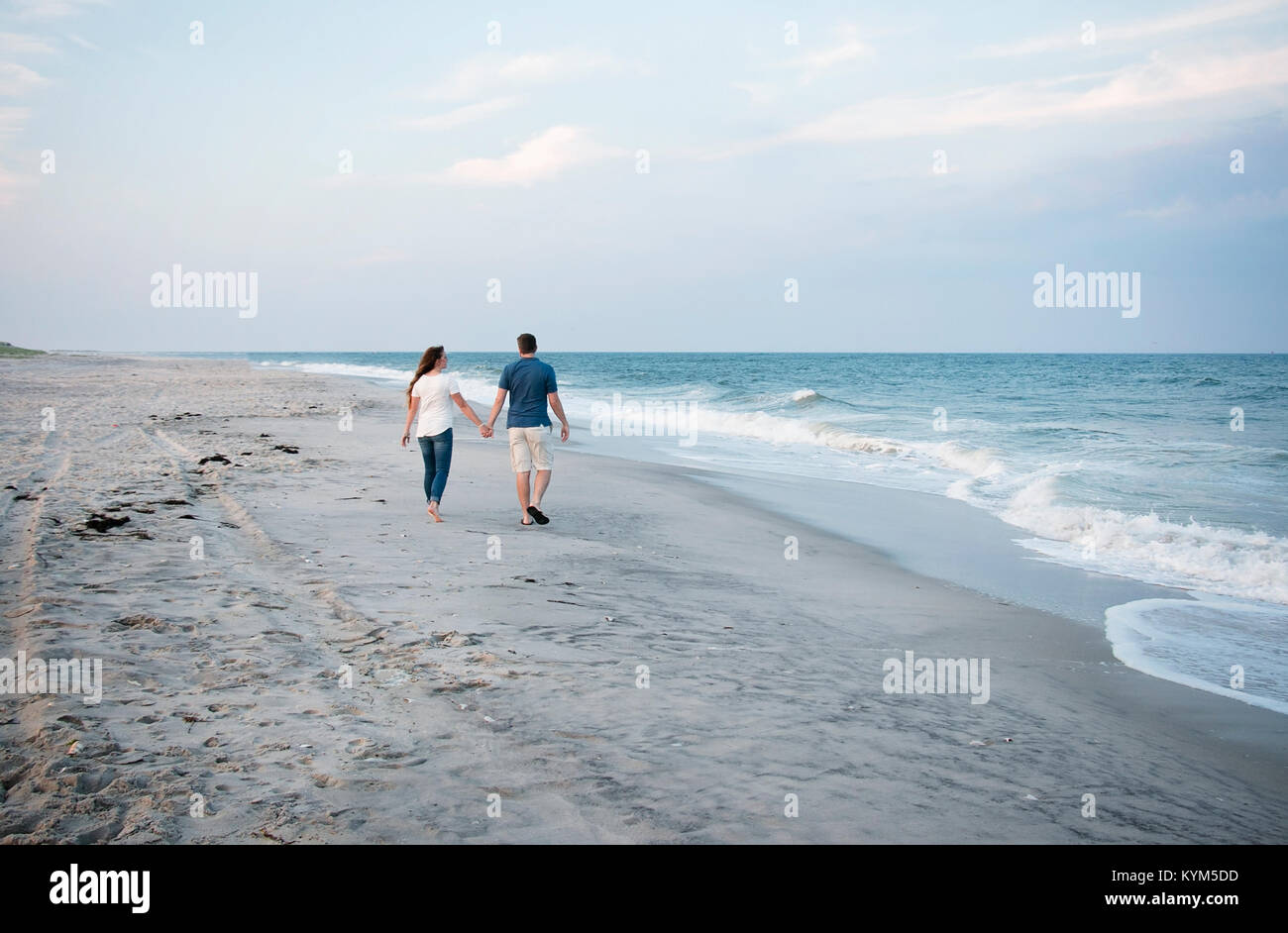 Couple holding hands, walking on the beach Stock Photo - Alamy