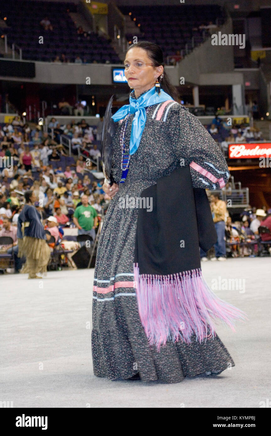 A Native American woman dressed in traditional regalia performing a ...