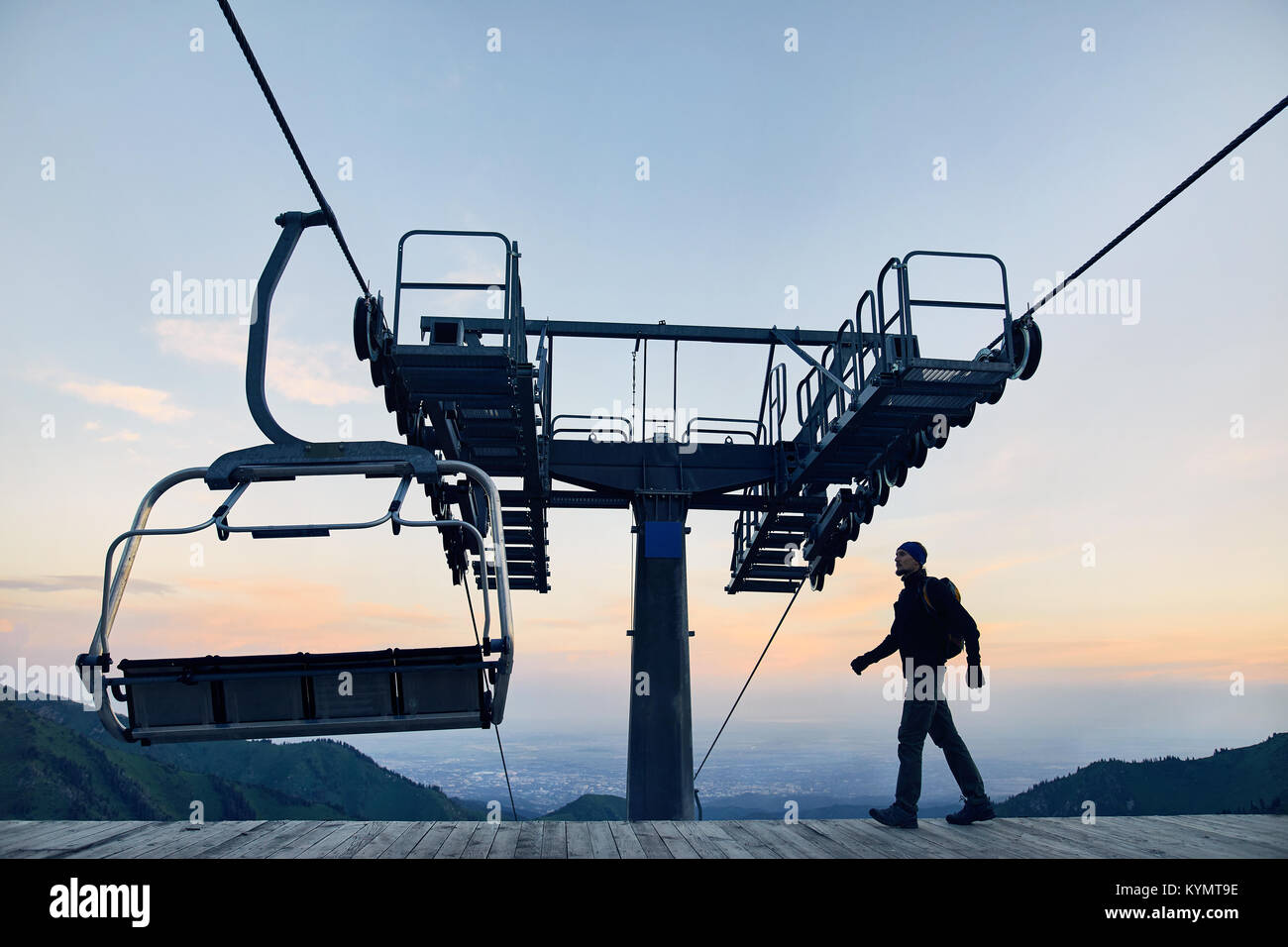 Tourist man walking at ski lift station in silhouette high in mountain ski resort at sunrise Stock Photo