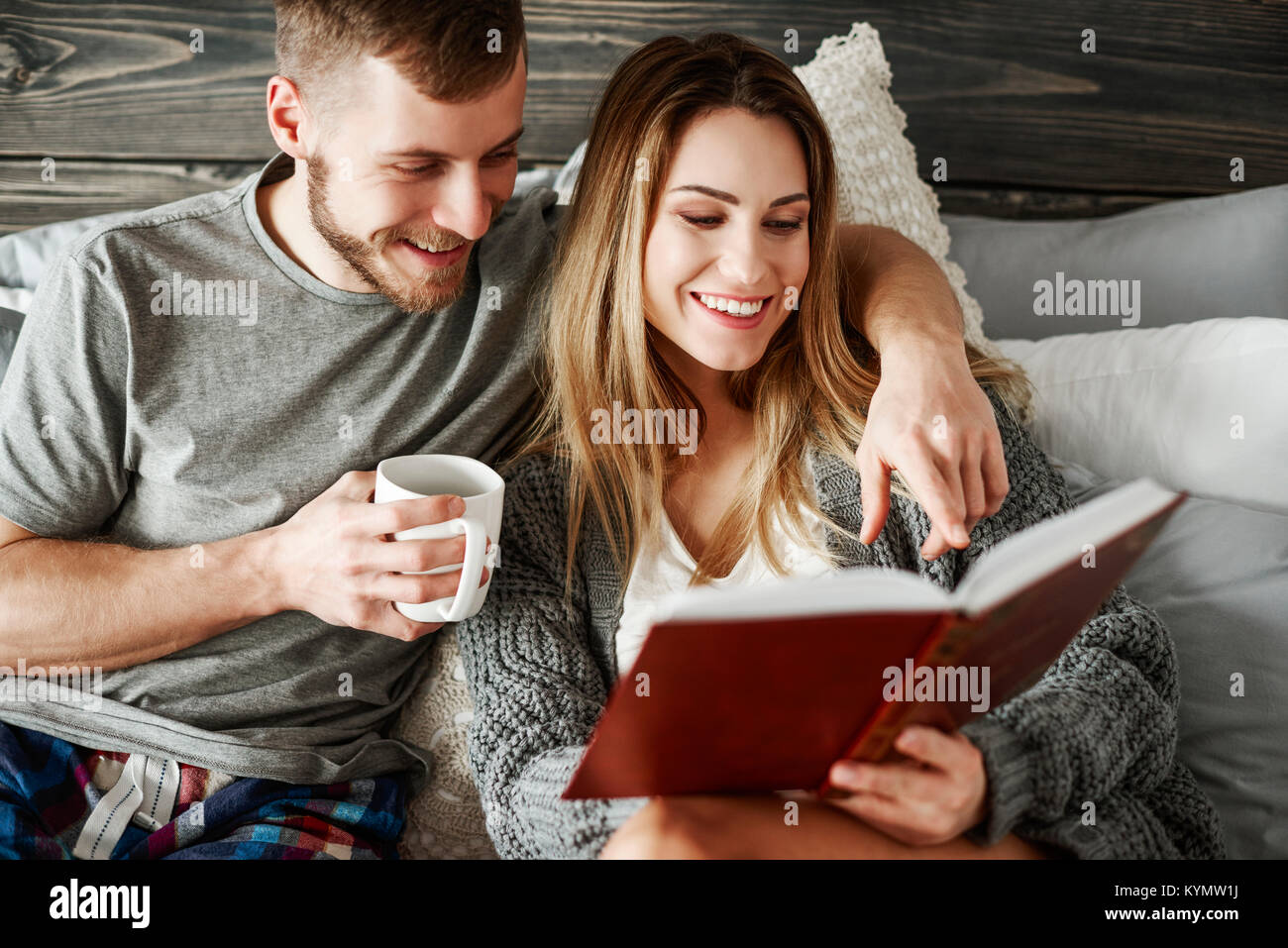 Young couple reading book at bedroom Stock Photo