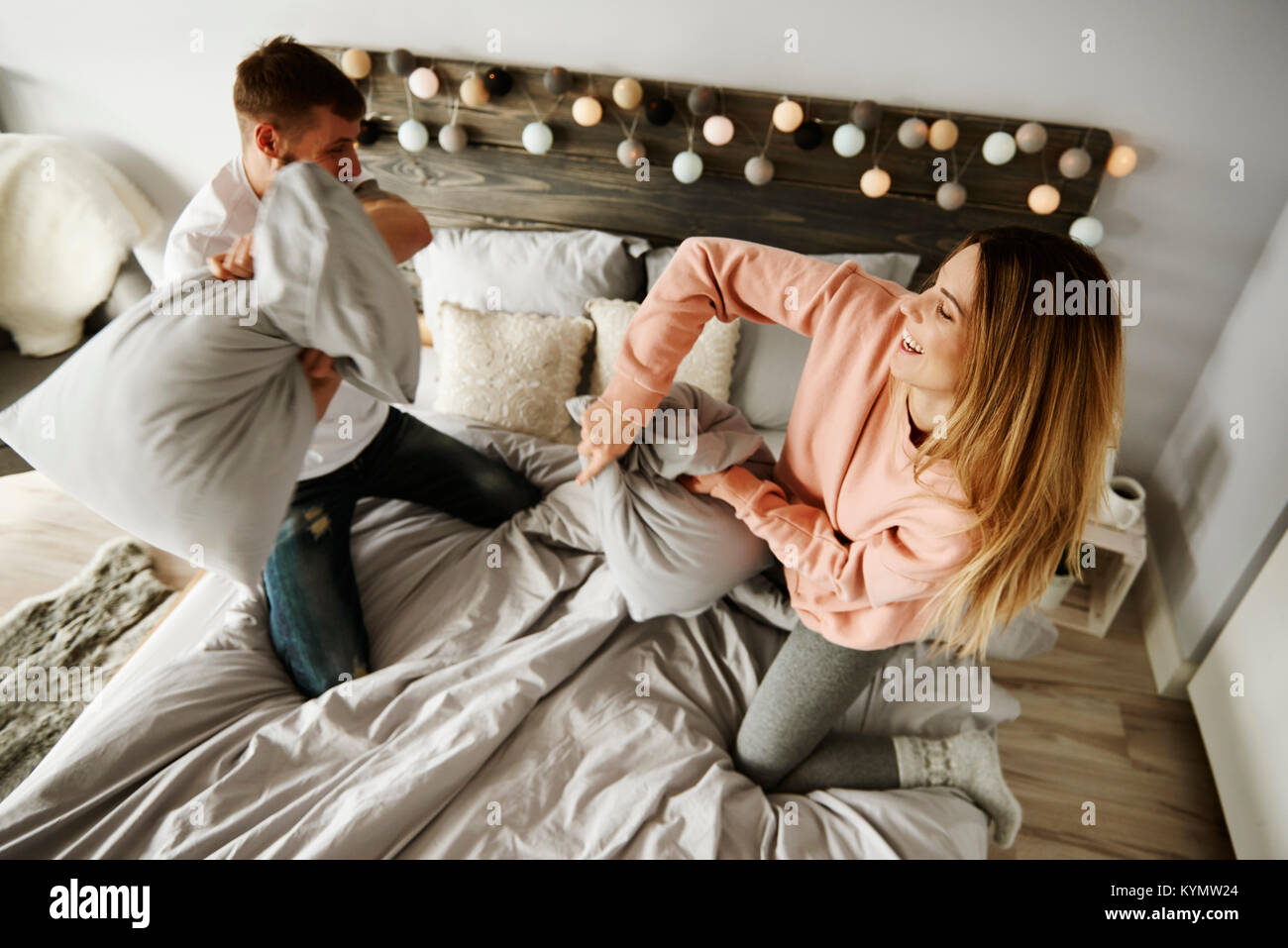 Couple fighting with pillows in bedroom Stock Photo
