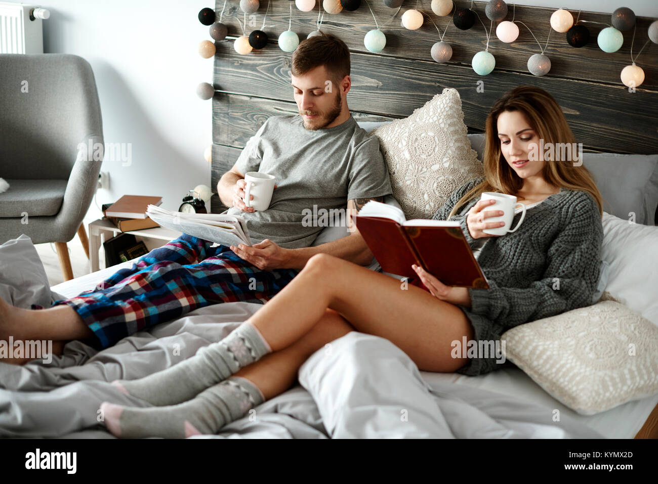 Couple with morning coffee reading at bedroom Stock Photo