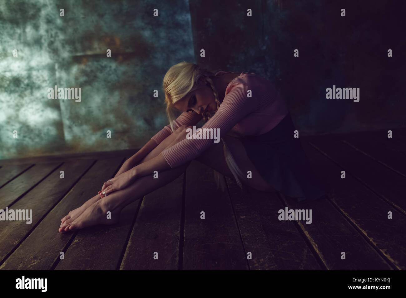 Beautiful blonde woman is sitting on the wooden floor Stock Photo - Alamy