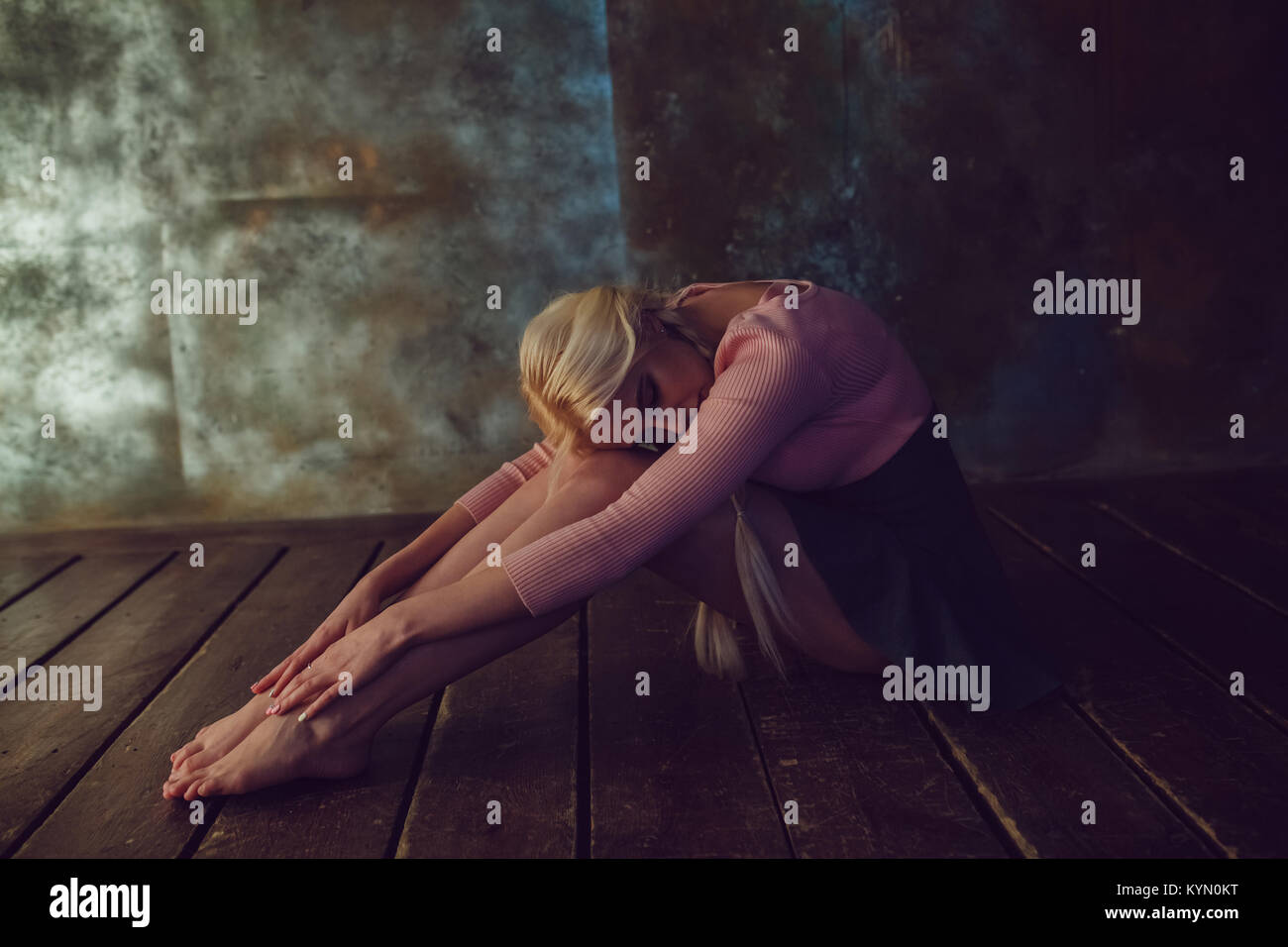 Beautiful blonde woman is sitting on the wooden floor Stock Photo - Alamy