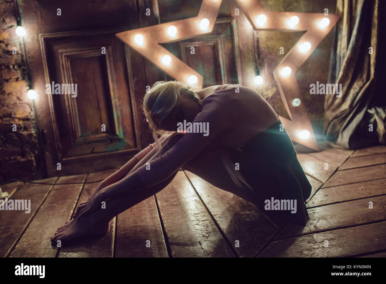 Beautiful blonde woman is sitting on the wooden floor Stock Photo - Alamy