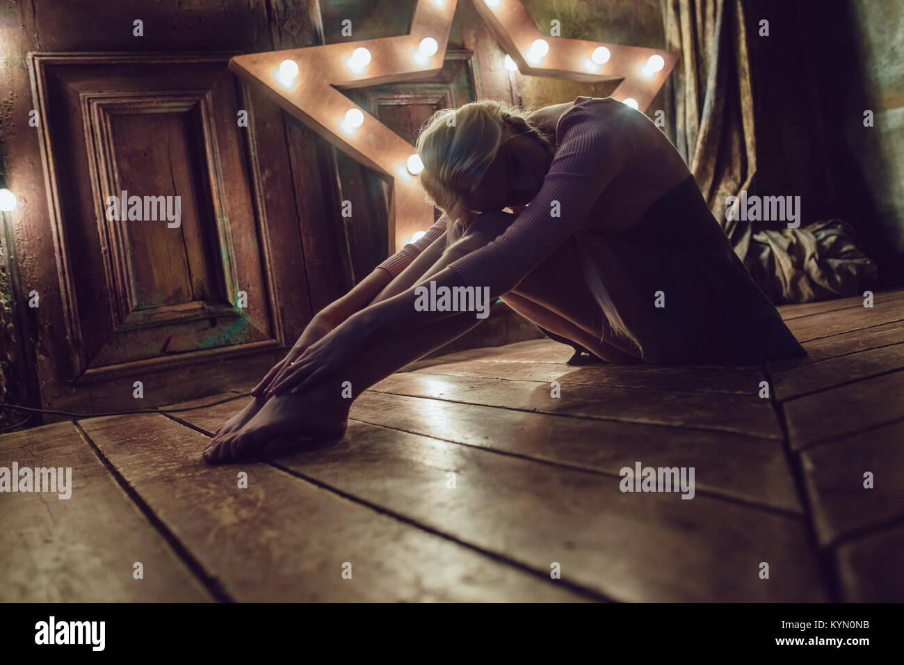 Beautiful blonde woman is sitting on the wooden floor Stock Photo - Alamy