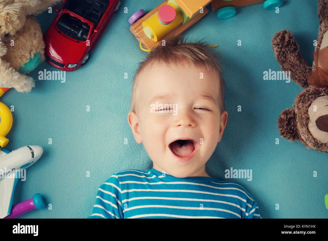 Happy one year old boy lying with many plush toys Stock Photo Alamy