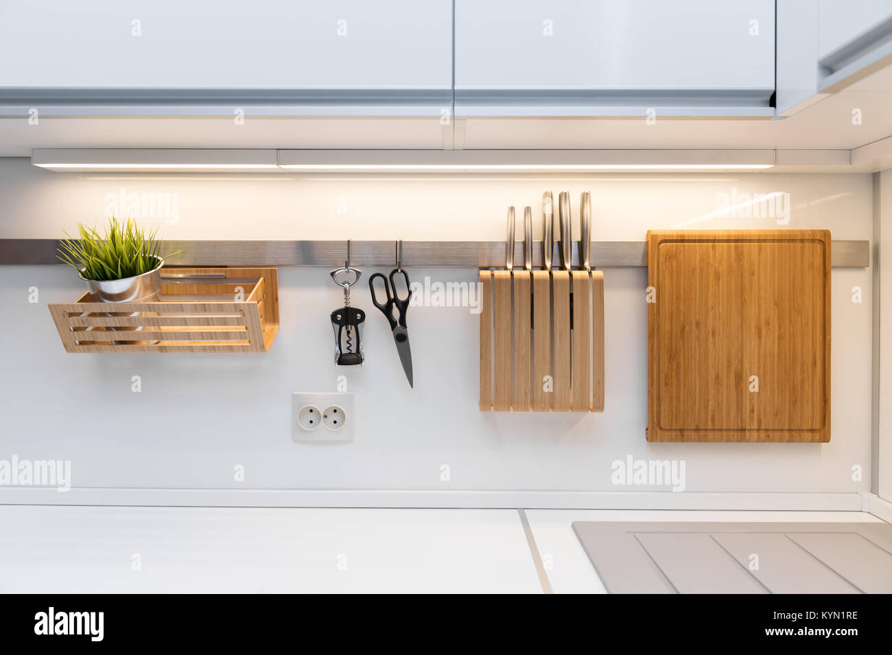 kitchenware hanging on the rail in the white glossy kitchen Stock Photo