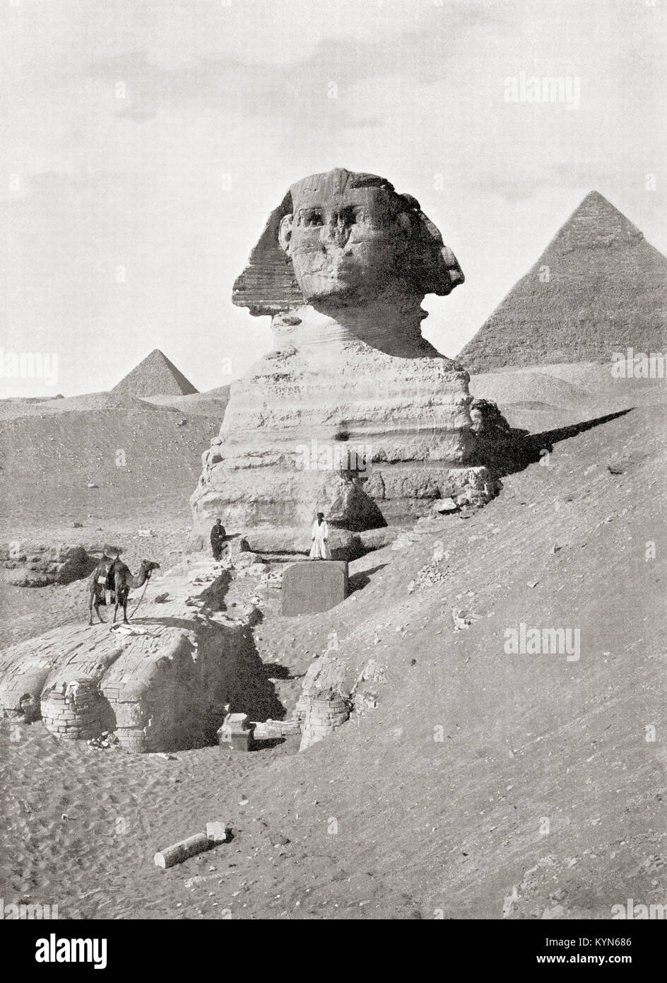 The Great Sphinx in The Giza pyramid complex, Giza Plateau, Cairo, Egypt.  A massive sculpture generally believed to represent the Pharaoh Khafre.  Seen here are workers clearing away sand which chokes the base of the monument.  From The Wonders of the World, published c.1920. Stock Photo