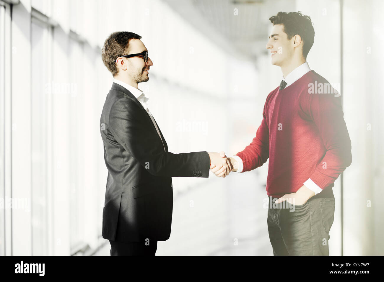 Full length of businessmen shaking hands in office building Stock Photo ...
