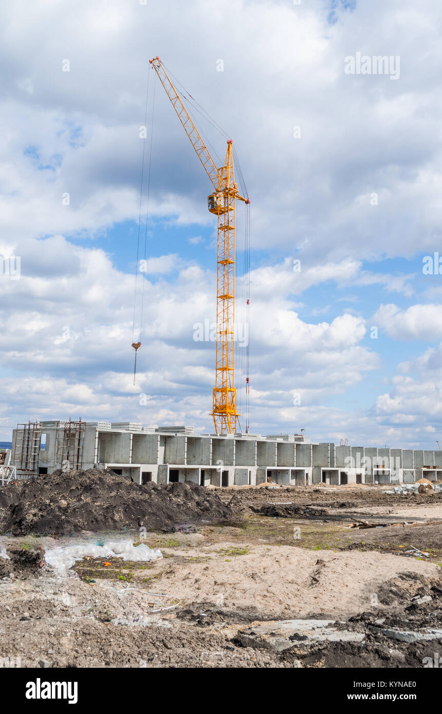 Lift crane building a new residential building on blue sky and white clouds. Stock Photo