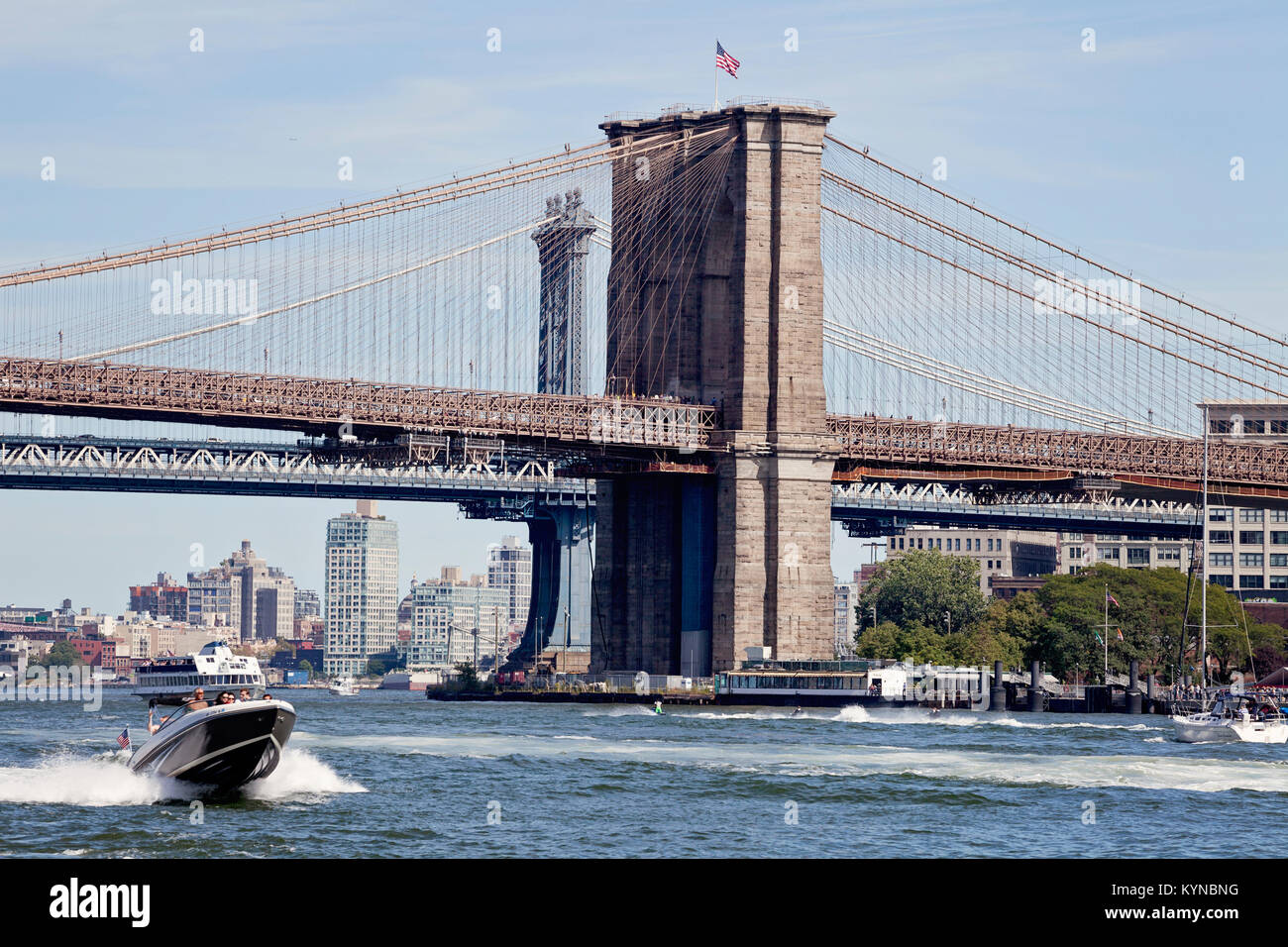 On the water, East River under the Brooklyn Bridge. Speed boat, ferry, jet skis. Manhattan,  New York. Stock Photo