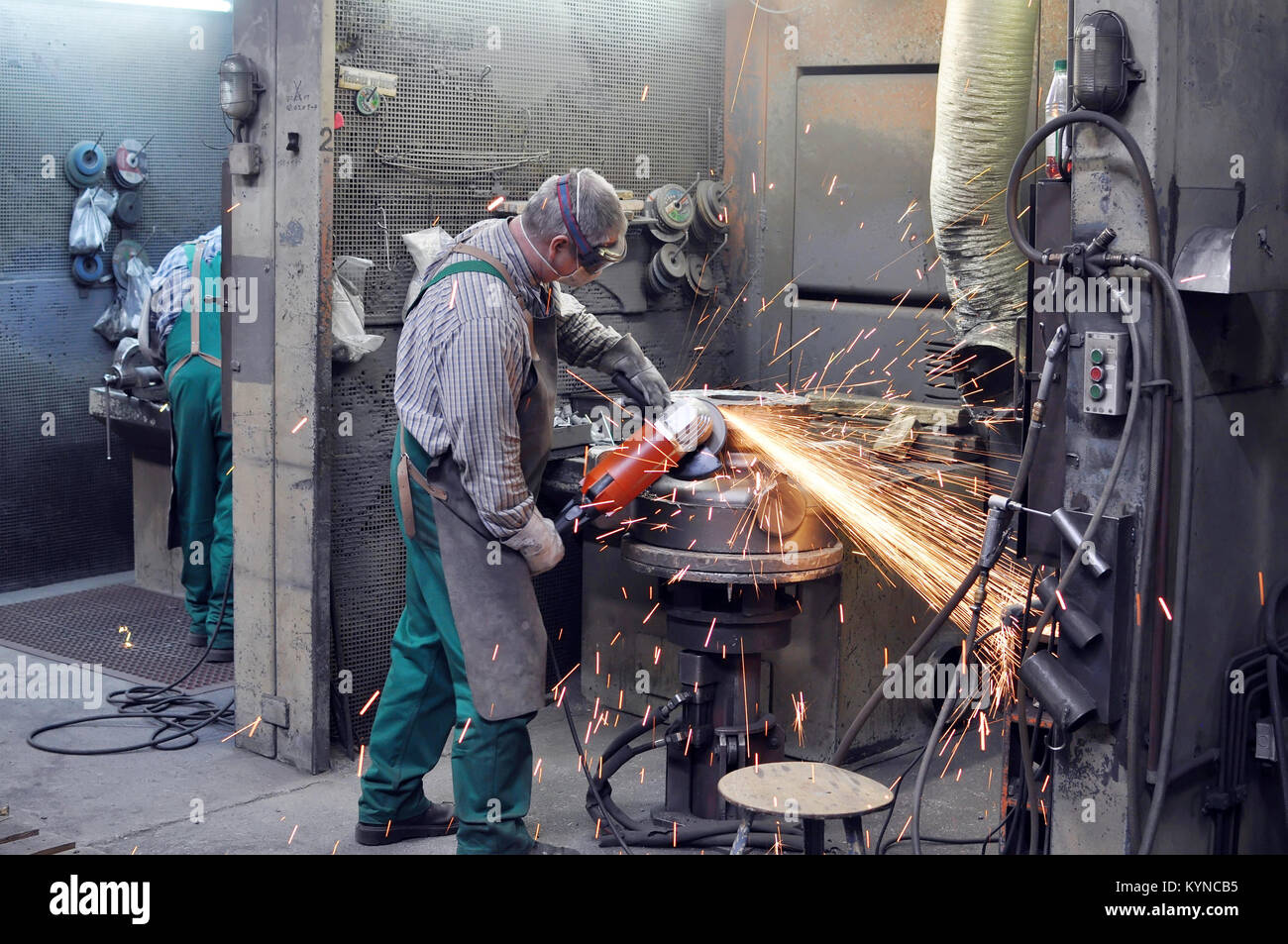 Workers in a foundry grind castings with a grinding machine Heavy