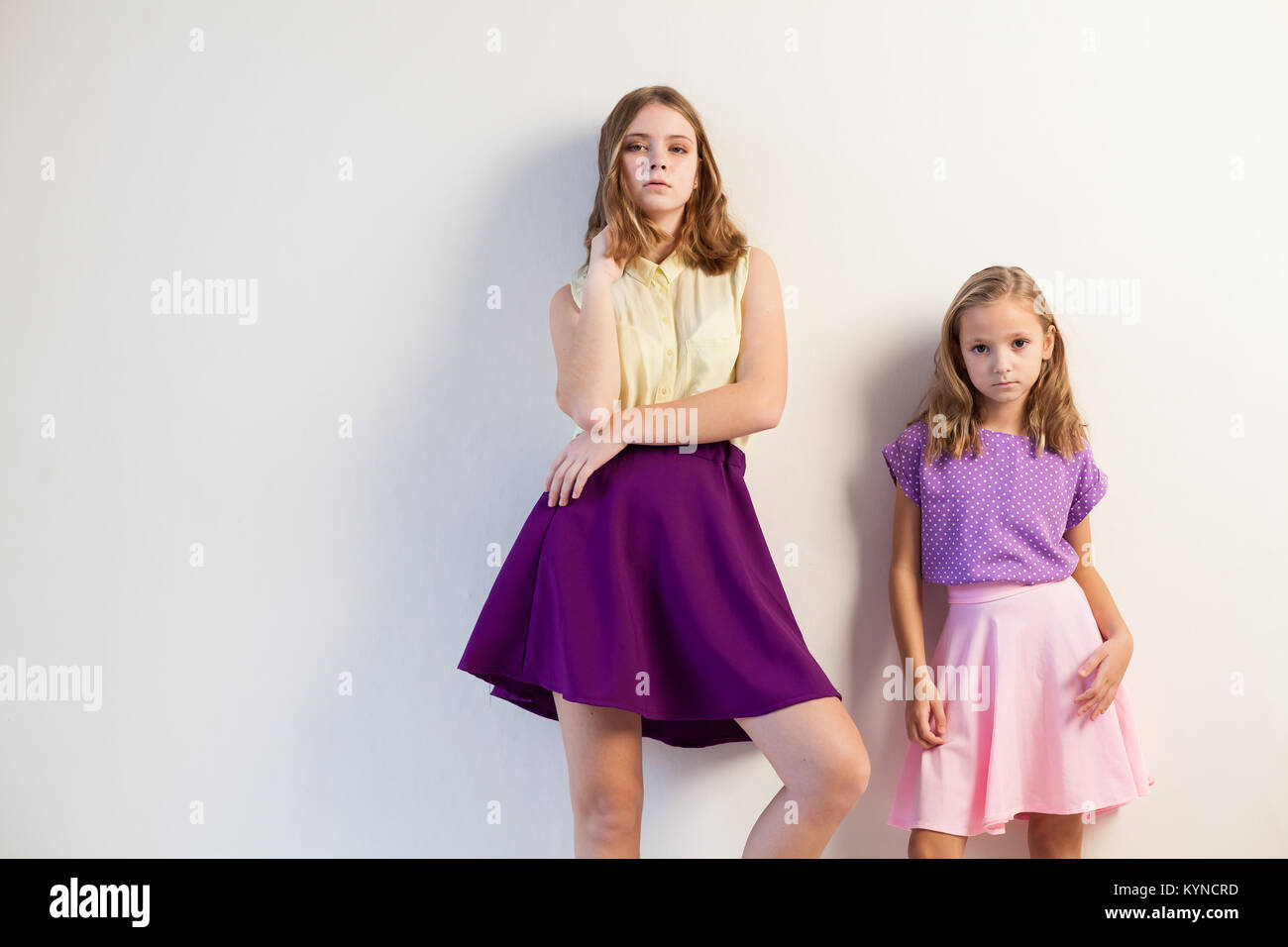 two sisters girls in colored dresses white walls Stock Photo - Alamy