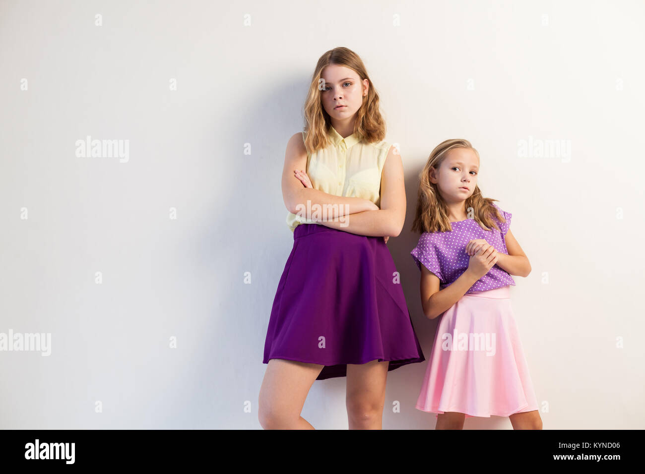 two sisters girls in colored dresses white walls Stock Photo - Alamy