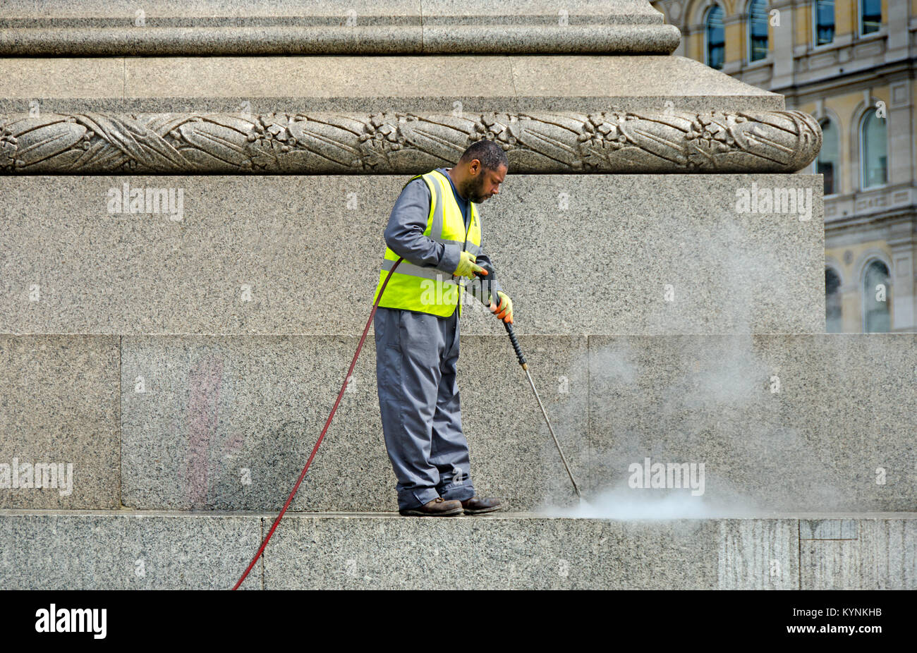 London, England, UK. Man cleaning the base of Nelson's Column with a pressure washer Stock Photo