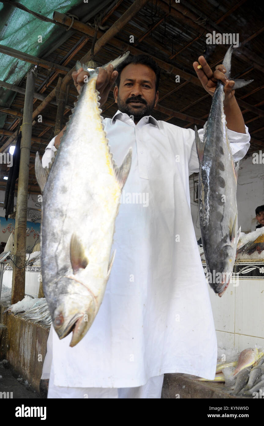 Karachi. 15th Jan, 2018. A man shows fish at a fish market in southern