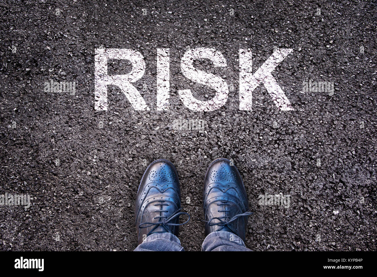 Word Risk written on an asphalt road with legs and shoes Stock Photo