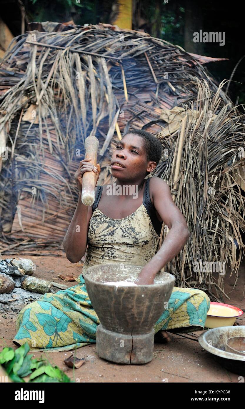 Africa. Jungle of the Central-African Republic. Baka woman cooks food, crushing a flour in a mortar Stock Photo