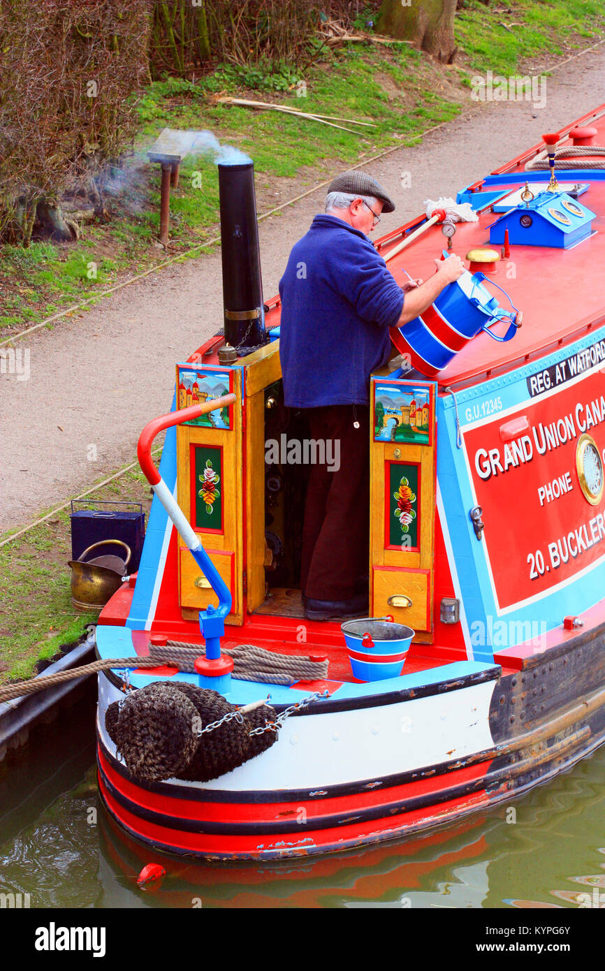 Narrowboat owner hand painting a bucket on board his  boat on the Grand Union canal Stock Photo