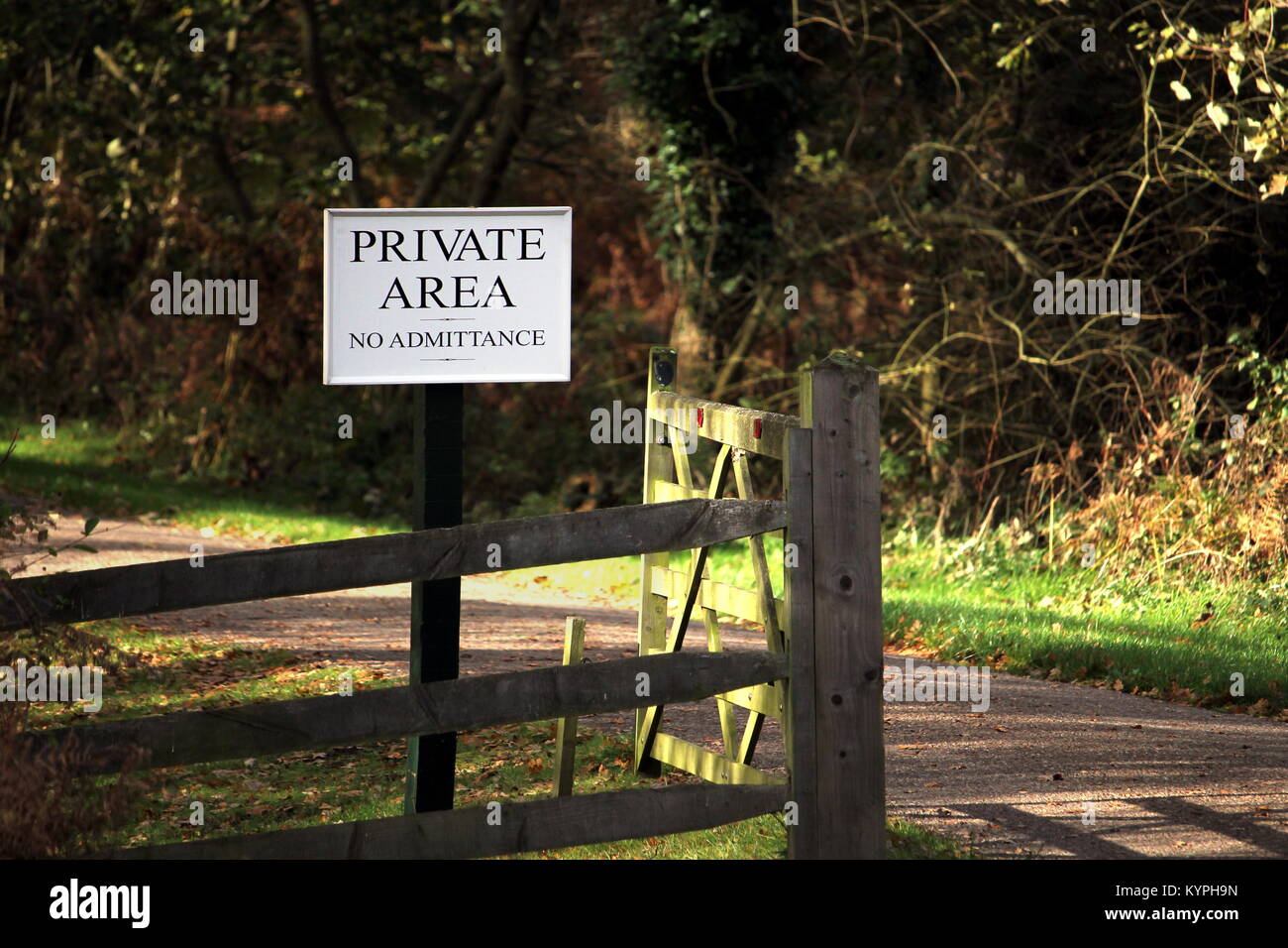 Wooden gate on a road through forest or woodland, with a sign saying 'PRIVATE AREA No Admittance' Stock Photo