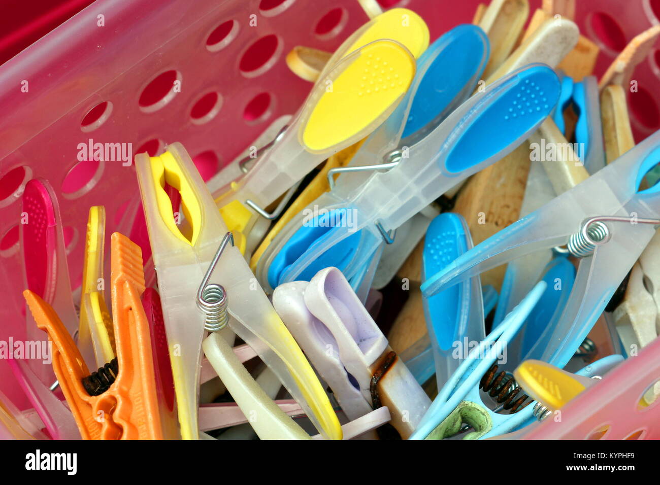 Closeup of brightly coloured clothes pegs or clothespins in a plastic container Stock Photo