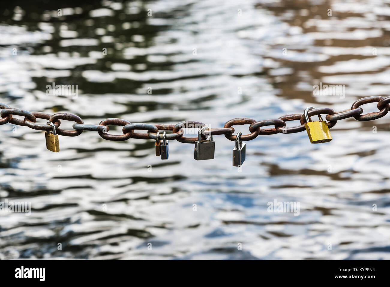 Padlocks attached to a chain as a sign of love for Valentine's Day with water in the background in Bruges, Belgium Stock Photo