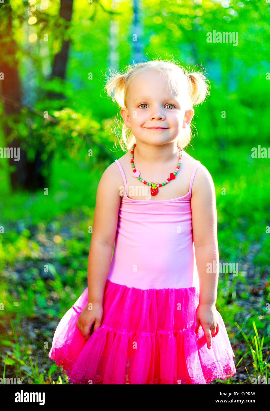 happy little girl wearing a pink dress in the summer park Stock Photo Alamy