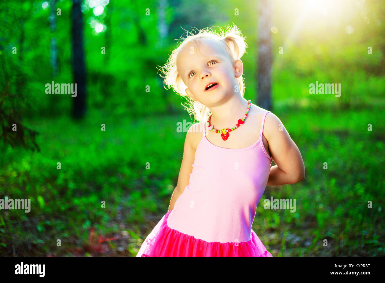 happy little girl wearing a pink dress, in the summer park Stock Photo ...