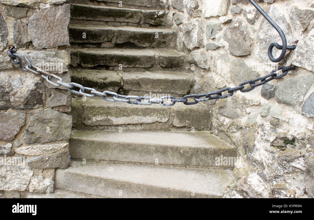 The chain that prevents the stair entry is located between the railing.Chain preventing entrance to the staircase. Stock Photo
