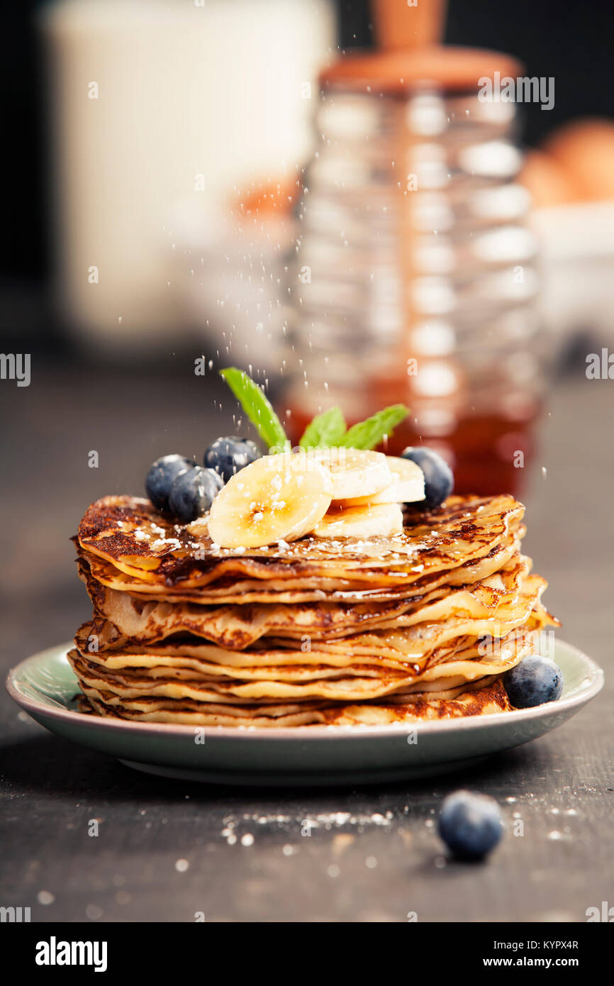 Pancake tower with fresh bananas, blueberries and honey on a rustic