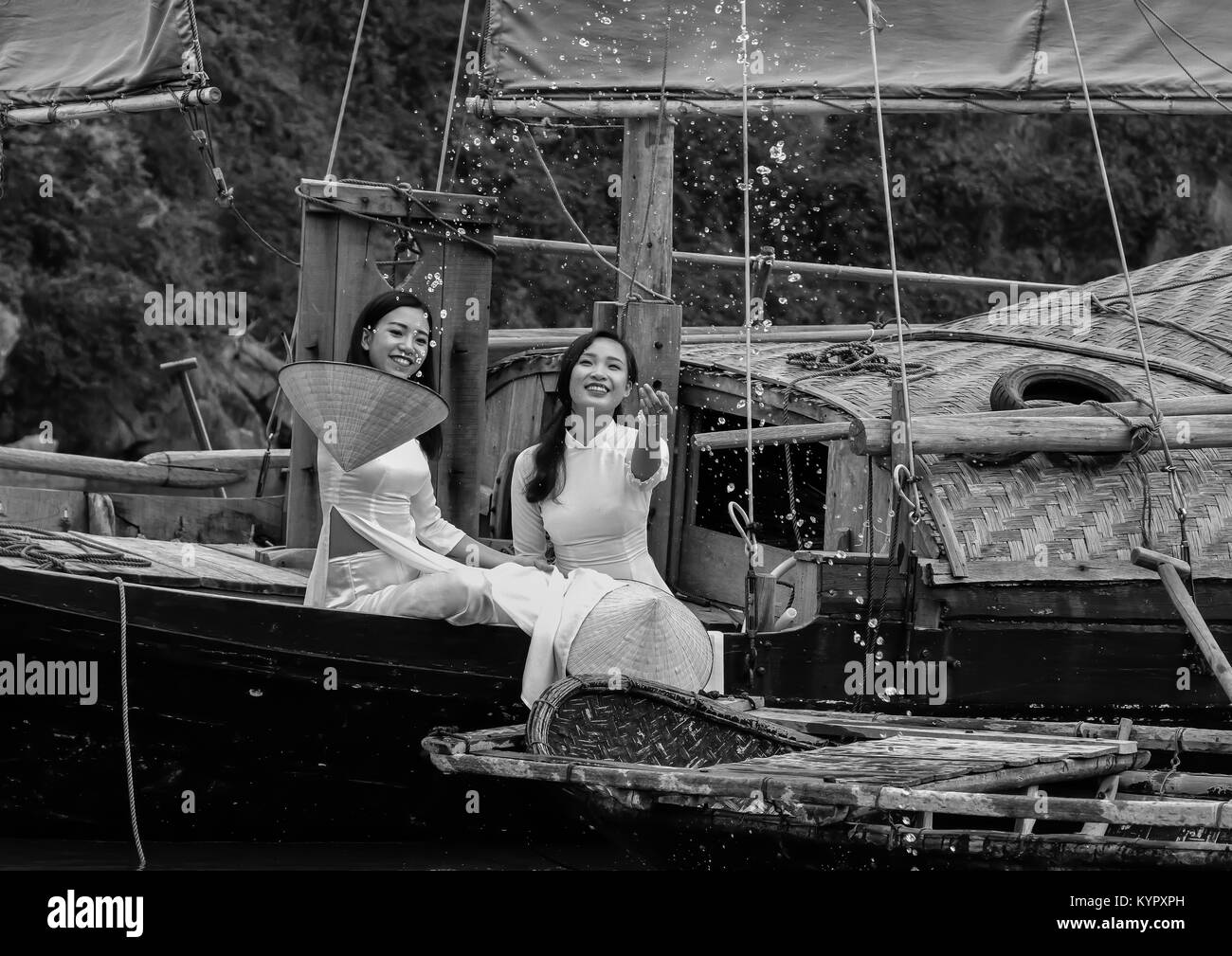 Young Vietnamese women having fun on a traditional junk. Halong Bay, Vietnam. They are wearing the traditional Ao Dai dress. Stock Photo