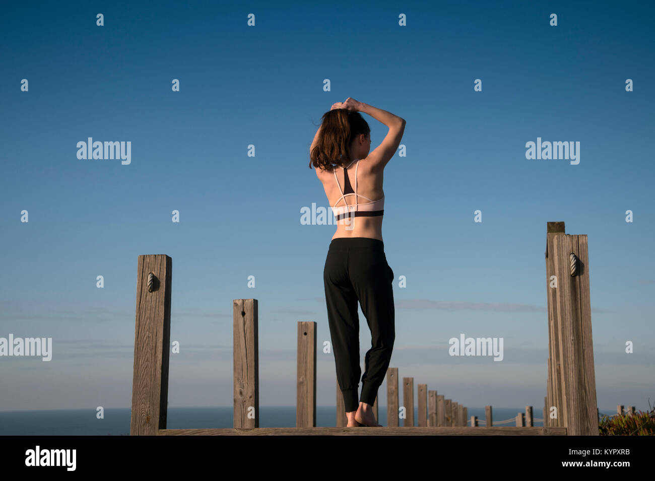 woman tying her hair back into a ponytail before fitness training outside by the sea. Stock Photo